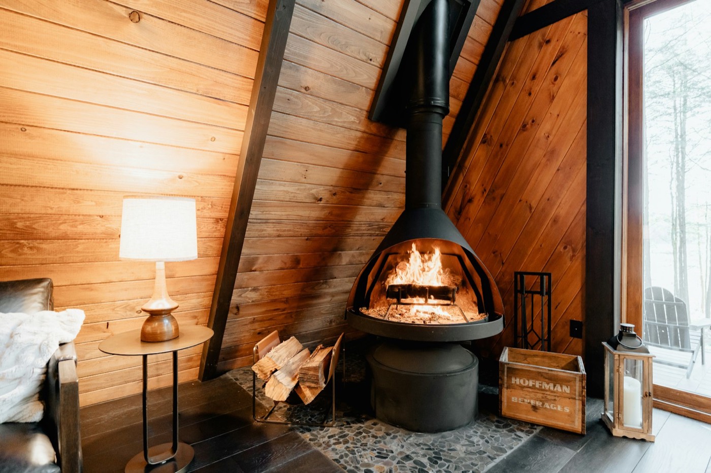 Poêle à bois suspendu noir allumé dans un intérieur tout en bois